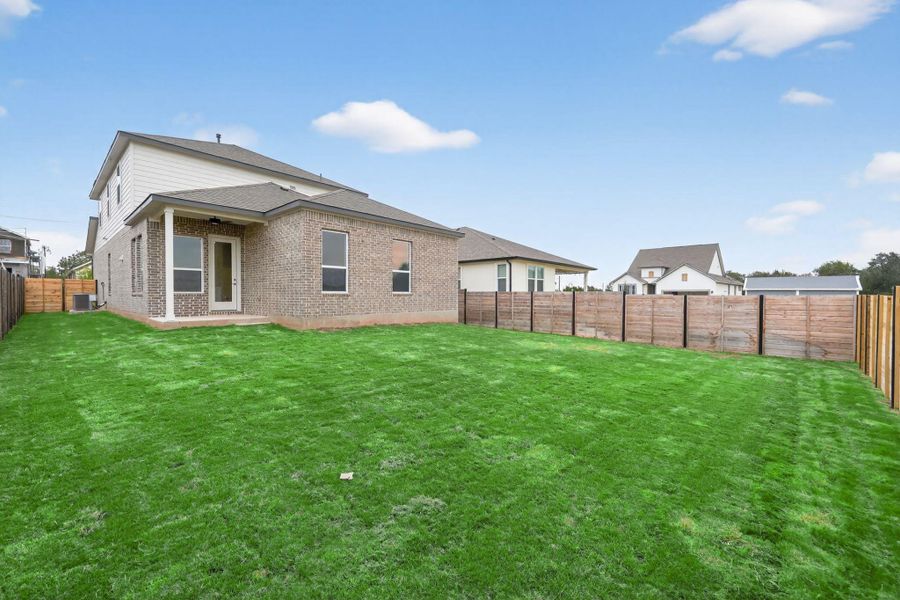 Rear view of property with a fenced backyard, a patio area, brick siding, and roof with shingles