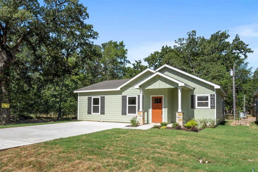 Single-story residence featuring light green siding and a vibrant orange entry door Single-story residence featuring light green siding and a vibrant orange entry door