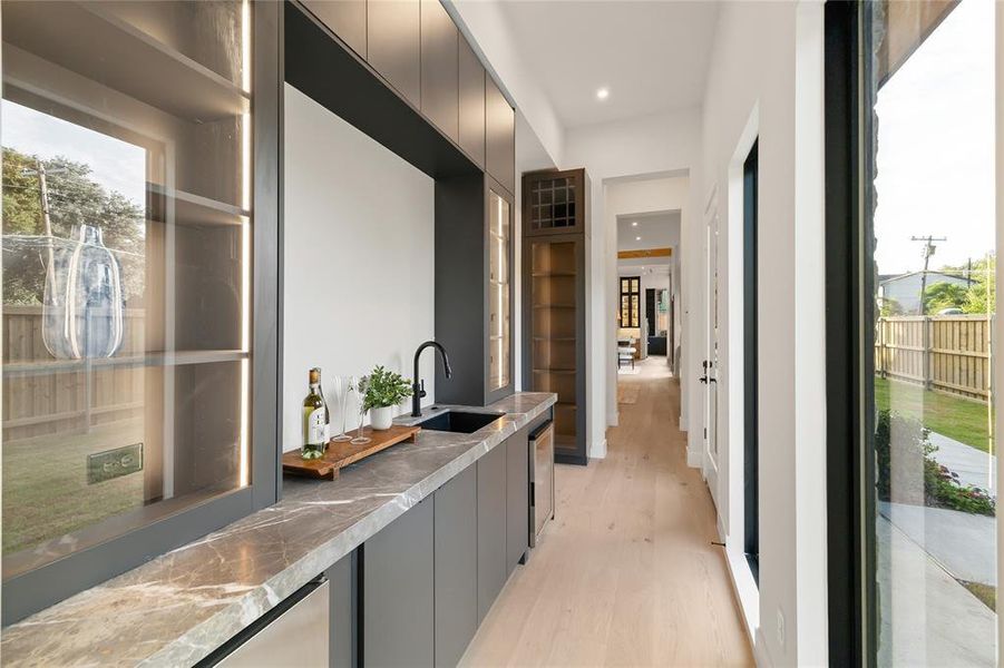 Wet bar featuring a dark stone countertop, integrated sink with matte black faucet, and under-counter refrigeration Wet bar featuring a dark stone countertop, integrated sink with matte black faucet, and under-counter refrigeration