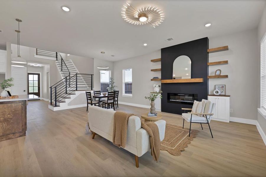 Living room with baseboards, stairway, a large fireplace, light wood finished floors, and recessed lighting Living room with baseboards, stairway, a large fireplace, light wood finished floors, and recessed lighting