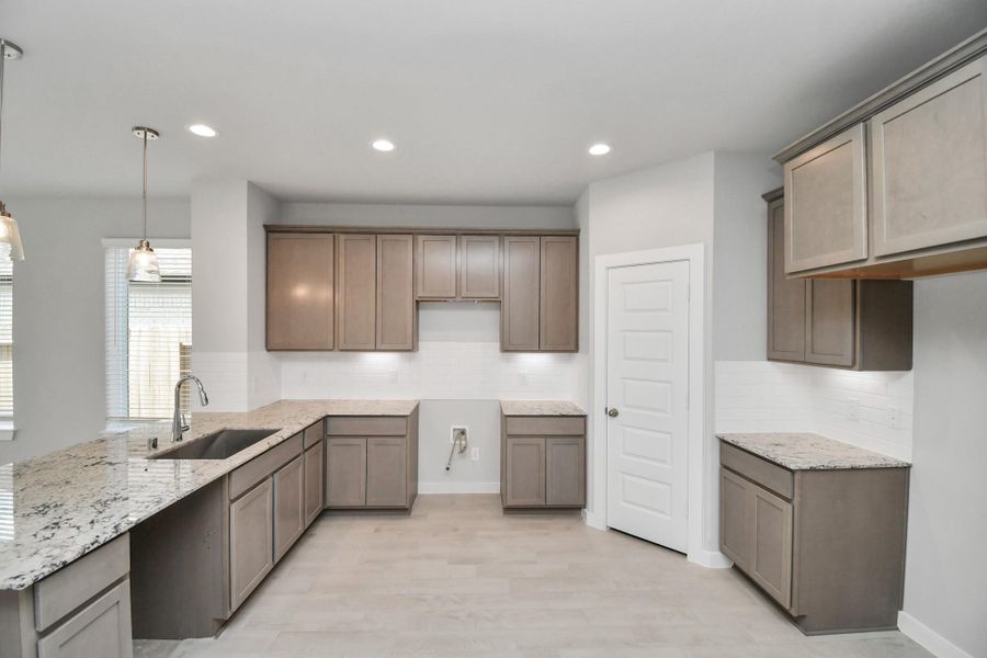 The kitchen is a culinary haven, featuring granite countertops, a tile backsplash, stainless steel appliances, 42” upper cabinets, and undercabinet lighting. Sample photo of completed home with similar floor plan. Actual colors and selections may vary.
