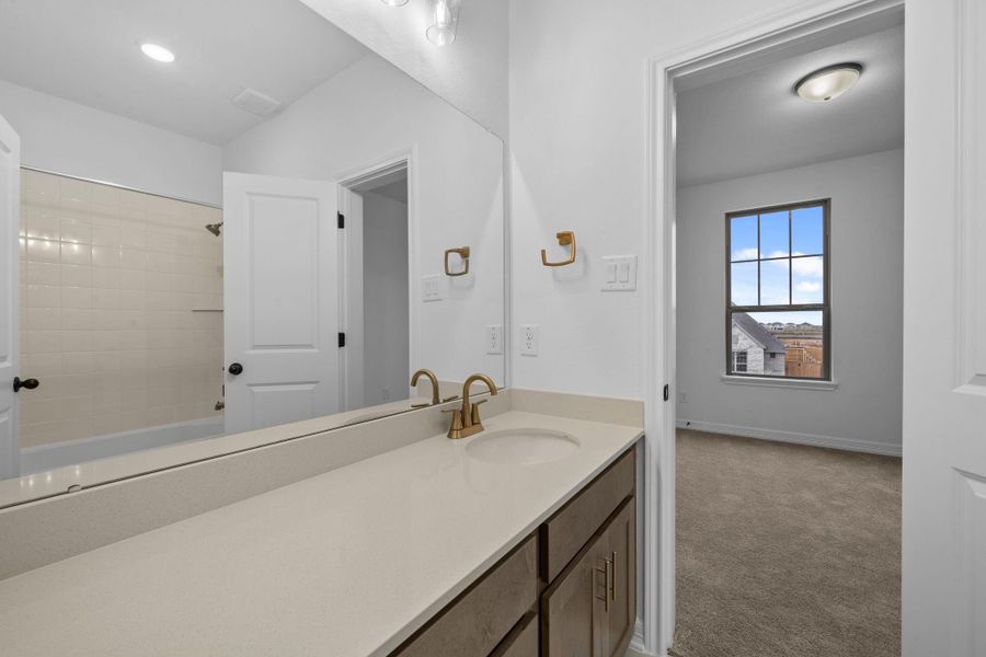 Modern bath featuring the AW Collection Laguna with stained cabinetry, light countertops with brass fixtures and a convenient shower/tub combo.