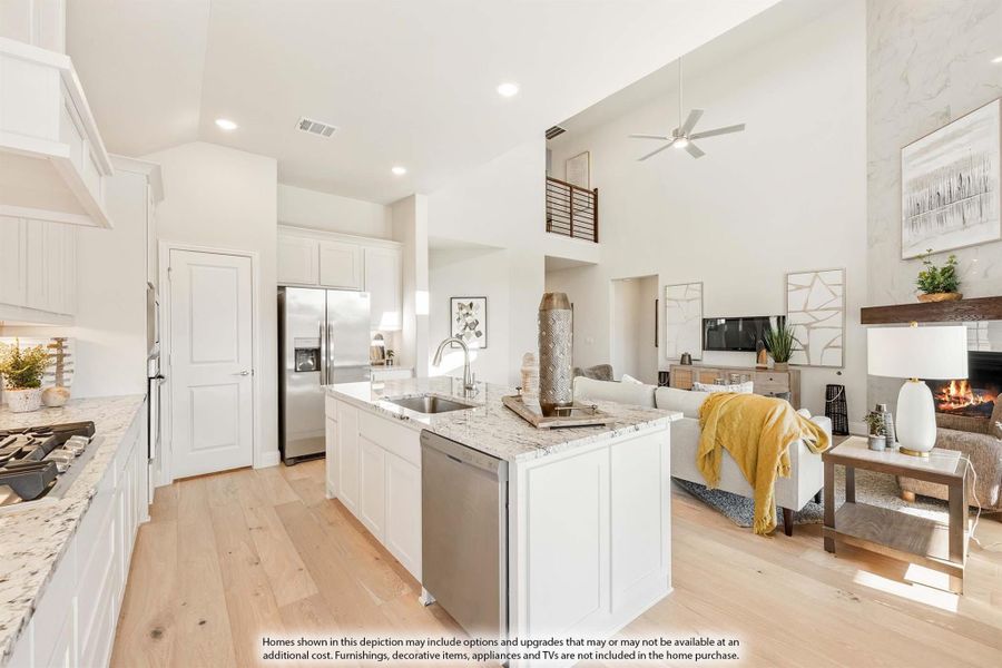 Open-concept kitchen with white island, granite countertops, and living room with fireplace and high ceilings Open-concept kitchen with white island, granite countertops, and living room with fireplace and high ceilings