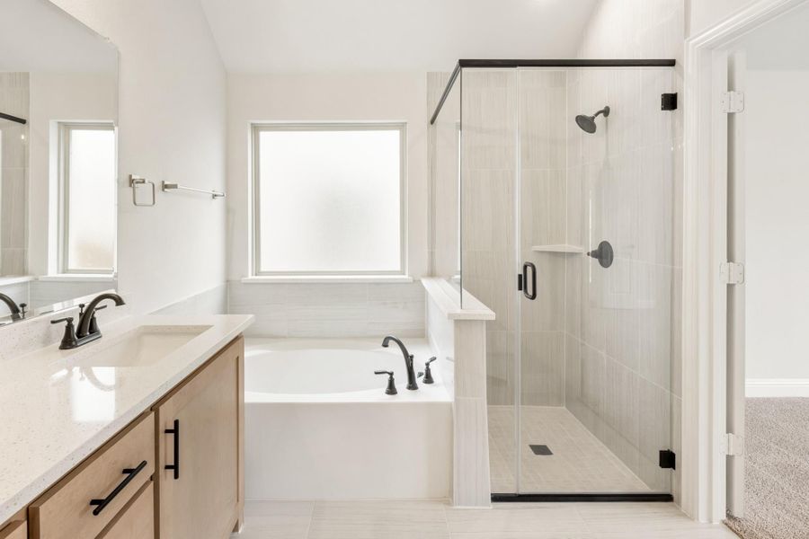 Master bathroom with soaking tub, glass walk-in shower, and wood vanity with quartz countertop