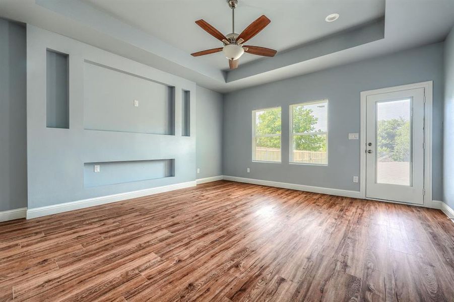 Unfurnished living room featuring a tray ceiling, hardwood / wood-style floors, and ceiling fan