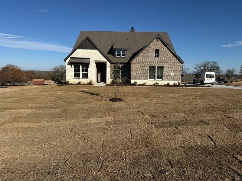 View of front of property with stone siding, a chimney, and a front yard View of front of property with stone siding, a chimney, and a front yard