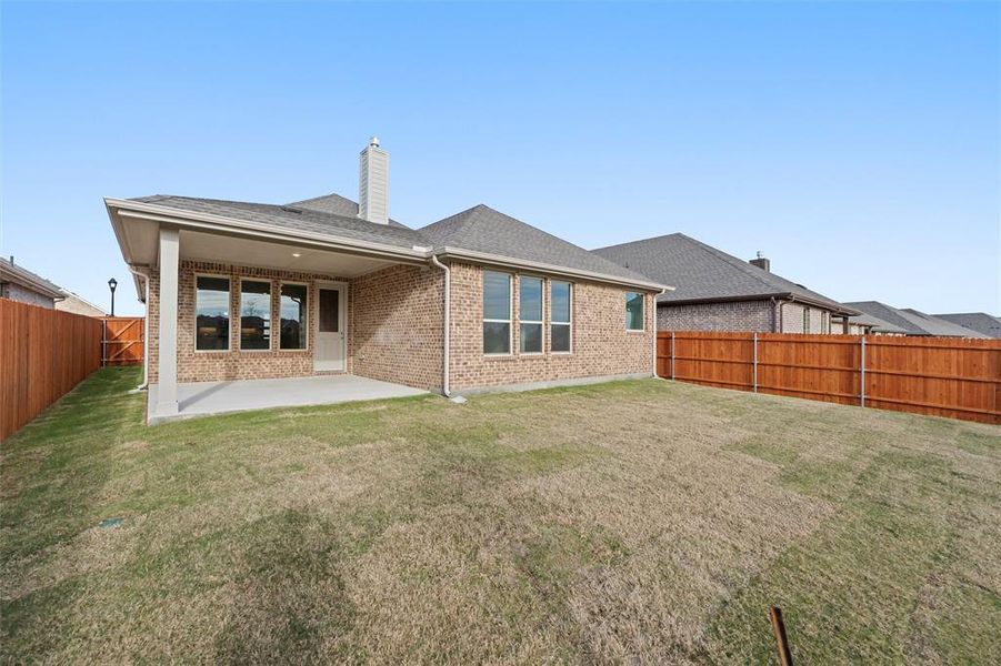 Rear view of property featuring a fenced backyard, brick siding, a shingled roof, a patio area, and a chimney