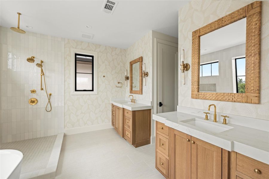 Bathroom featuring walk in shower, wallpapered walls, two vanities, and baseboards