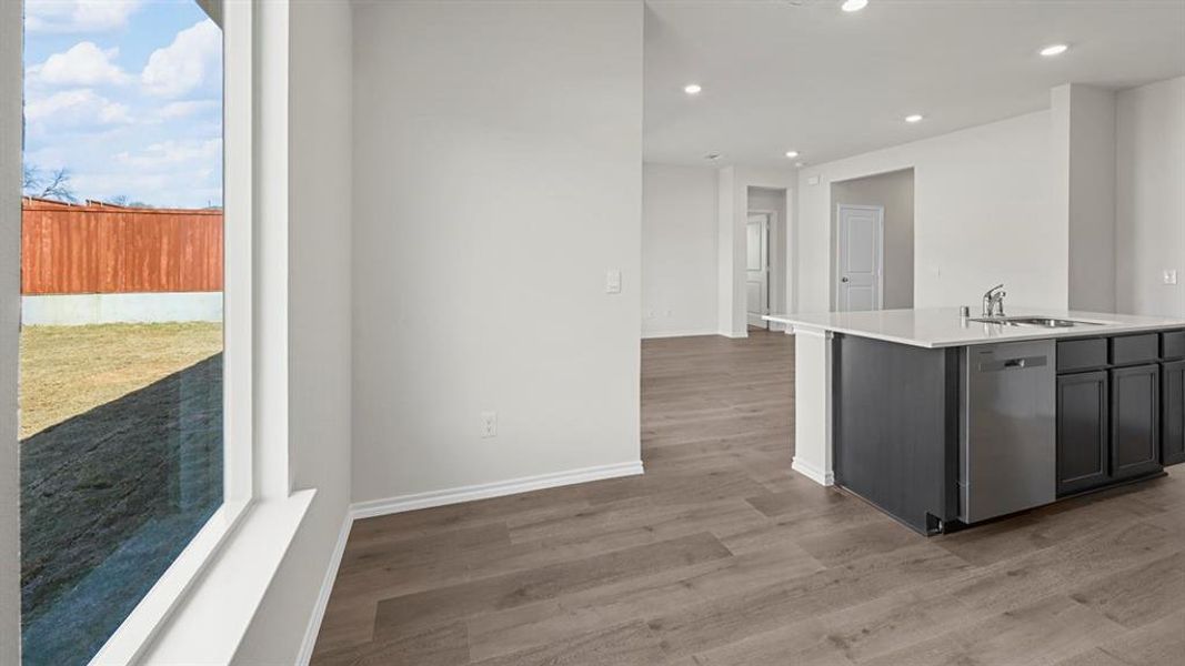 Kitchen with recessed lighting, dishwasher, a center island with sink, light wood-style flooring, and light stone countertops