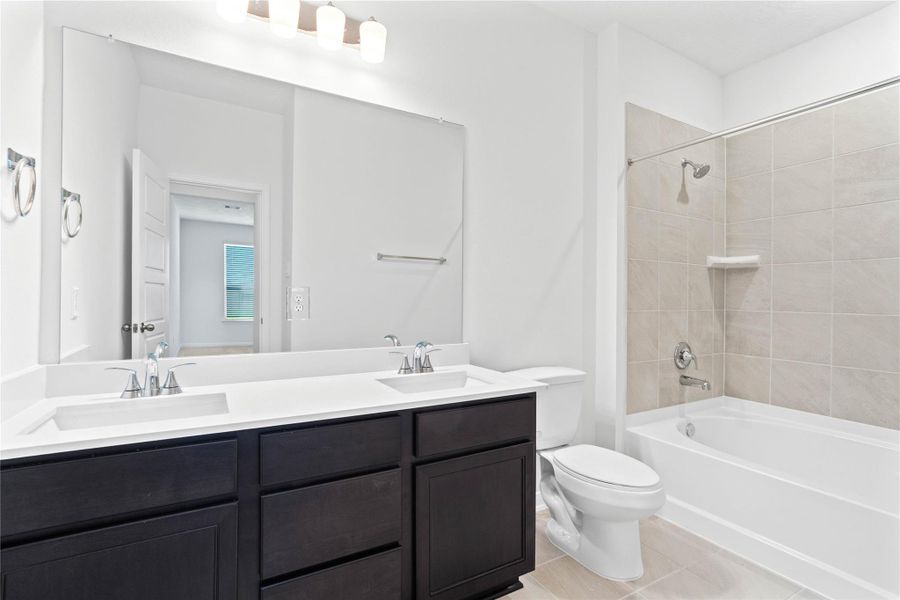 This stunningly updated primary bathroom is truly move-in ready! It features dark stained cabinetry with light countertops, dual sinks, a large mirror, high ceilings, custom paint, and sleek modern finishes throughout.