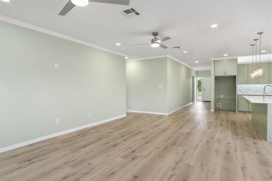 Unfurnished room featuring ornamental molding, ceiling fan with notable chandelier, and light wood-type flooring