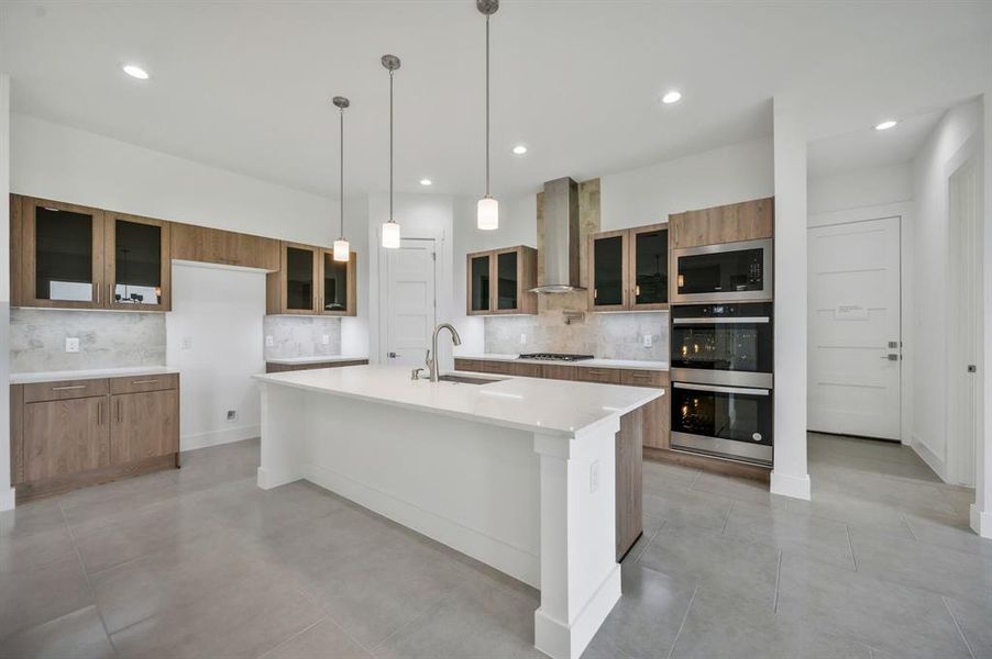 Kitchen featuring wall chimney range hood, appliances with stainless steel finishes, a sink, decorative backsplash, and modern cabinets Kitchen featuring wall chimney range hood, appliances with stainless steel finishes, a sink, decorative backsplash, and modern cabinets