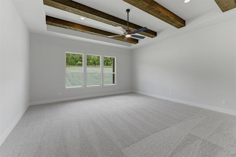 Spacious room featuring a tray ceiling with exposed wood beams, a ceiling fan, and recessed lighting