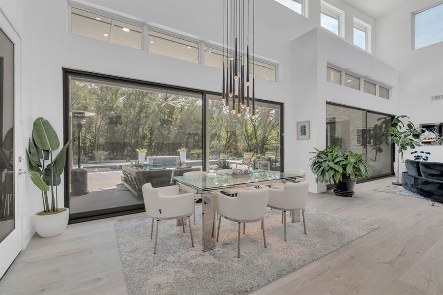 Dining space with light wood-style flooring, a high ceiling, and a chandelier