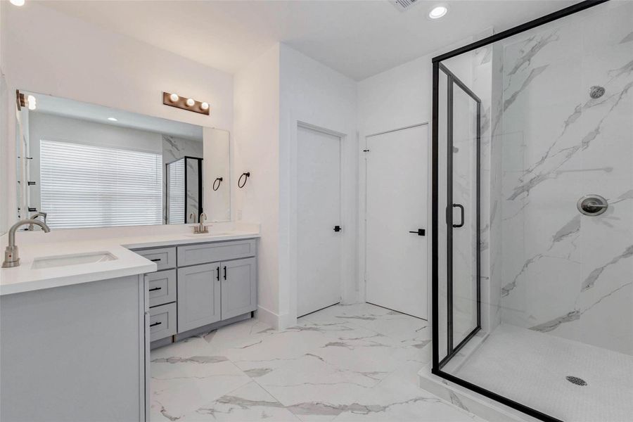 The generously sized bathroom delivers a crisp, spa-inspired atmosphere with a dual-sink vanity, expansive mirror, marble-inspired flooring, and a glass-enclosed walk-in shower. Black framing and hardware introduce modern contrast, while abundant lighting keeps the space bright, polished, and functional. The generously sized bathroom delivers a crisp, spa-inspired atmosphere with a dual-sink vanity, expansive mirror, marble-inspired flooring, and a glass-enclosed walk-in shower. Black framing and hardware introduce modern contrast, while abundant lighting keeps the space bright, polished, and functional.