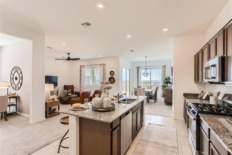 Kitchen with appliances with stainless steel finishes, light stone countertops, a kitchen bar, light carpet, and recessed lighting