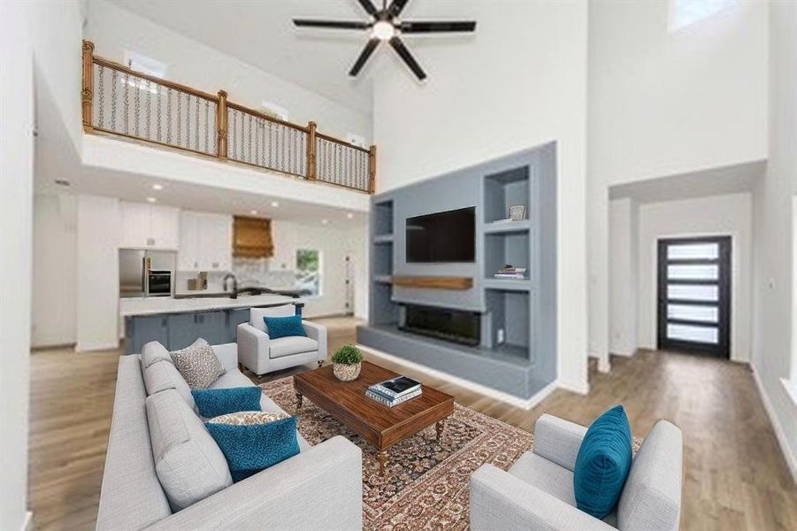 Living room featuring a towering ceiling, ceiling fan, light wood finished floors, built in features, and baseboards Living room featuring a towering ceiling, ceiling fan, light wood finished floors, built in features, and baseboards