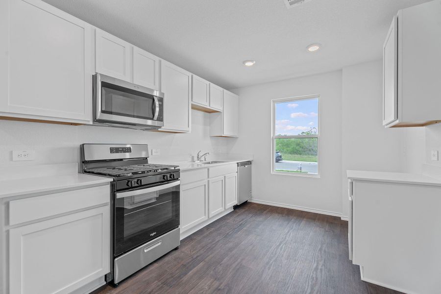 Kitchen with white cabinetry, dark wood-style floors, light countertops, appliances with stainless steel finishes, and recessed lighting Kitchen with white cabinetry, dark wood-style floors, light countertops, appliances with stainless steel finishes, and recessed lighting