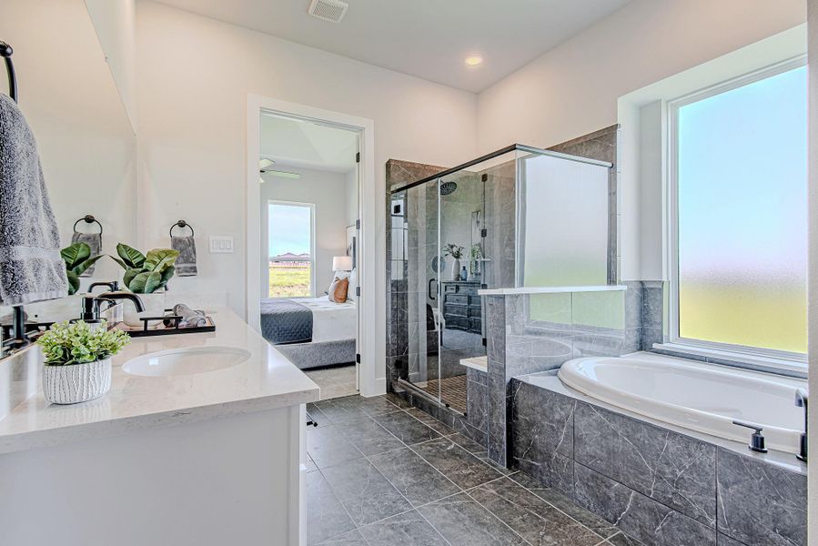 The elegant en-suite bath features a glass-enclosed shower, soaking tub, and direct access to the spacious primary suite—creating a seamless flow of comfort and function.