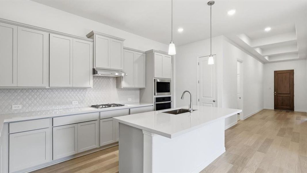 Contemporary kitchen featuring light-toned cabinetry, a spacious island with an undermount sink, and recessed lighting Contemporary kitchen featuring light-toned cabinetry, a spacious island with an undermount sink, and recessed lighting