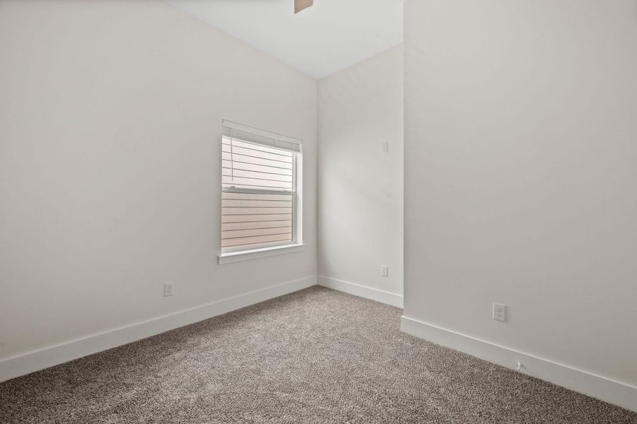 Bright and cozy room with soft carpet and a large window, perfect for a peaceful retreat or home office.