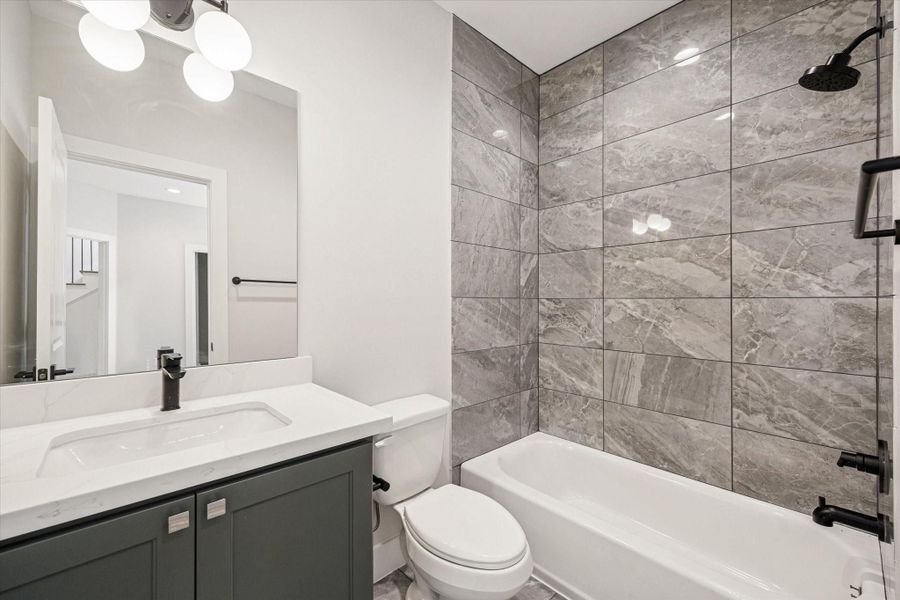 Ensuite bath with a shower/tub combo and quartz counters.