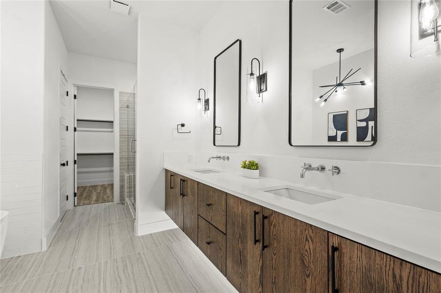 Bathroom featuring double vanity, a stall shower, and a walk in closet