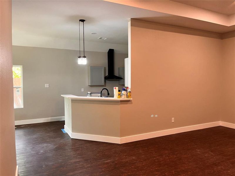 Kitchen featuring hanging light fixtures, dark hardwood / wood-style floors, and wall chimney range hood