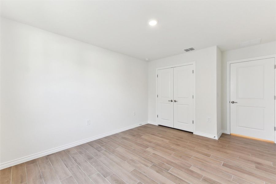 Unfurnished bedroom with visible vents, light wood-style flooring, and baseboards Unfurnished bedroom with visible vents, light wood-style flooring, and baseboards