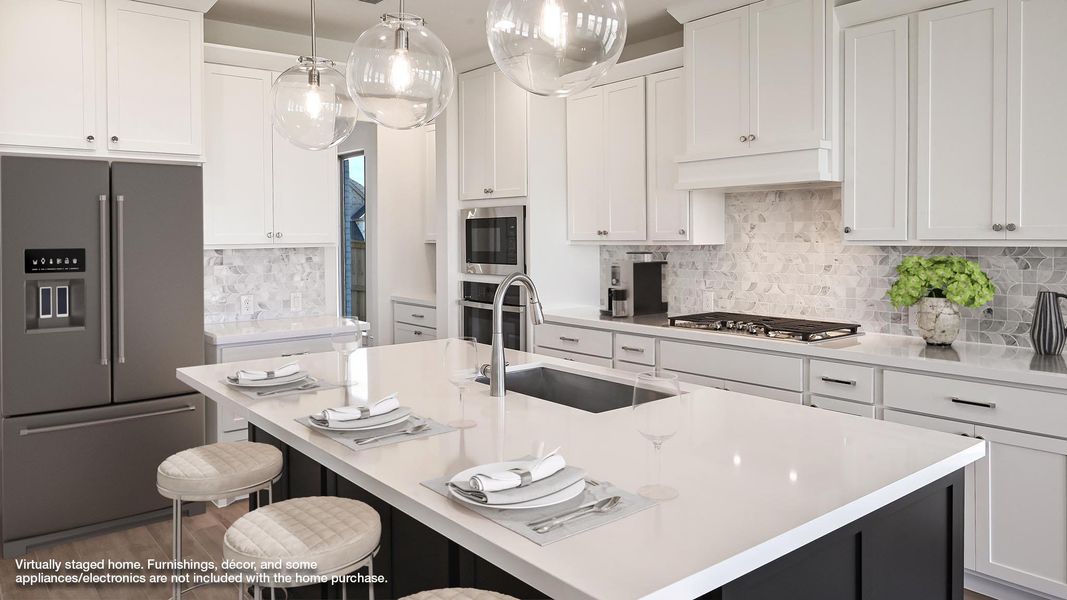 Kitchen featuring appliances with stainless steel finishes, a center island with sink, white cabinets, tasteful backsplash, and a kitchen bar