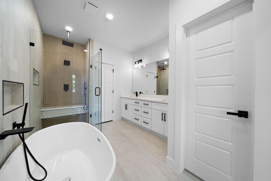 This primary bathroom features a modern design with a spacious glass-enclosed shower, a freestanding bathtub, and a double vanity. It has sleek black fixtures and ample lighting, creating a bright and luxurious feel. This primary bathroom features a modern design with a spacious glass-enclosed shower, a freestanding bathtub, and a double vanity. It has sleek black fixtures and ample lighting, creating a bright and luxurious feel.