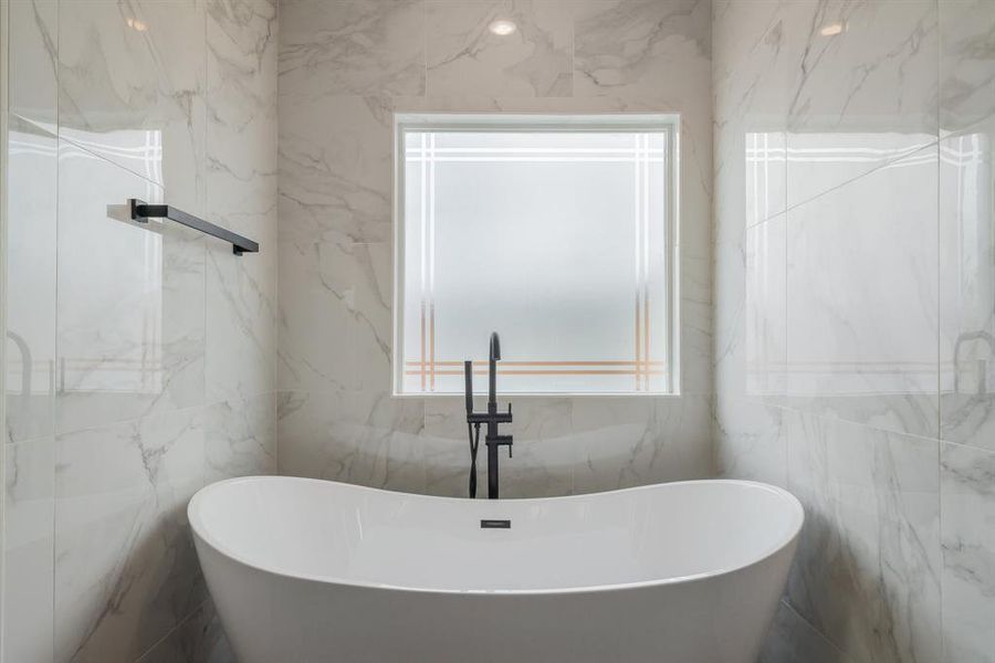 Bathroom featuring tile walls and a bathtub