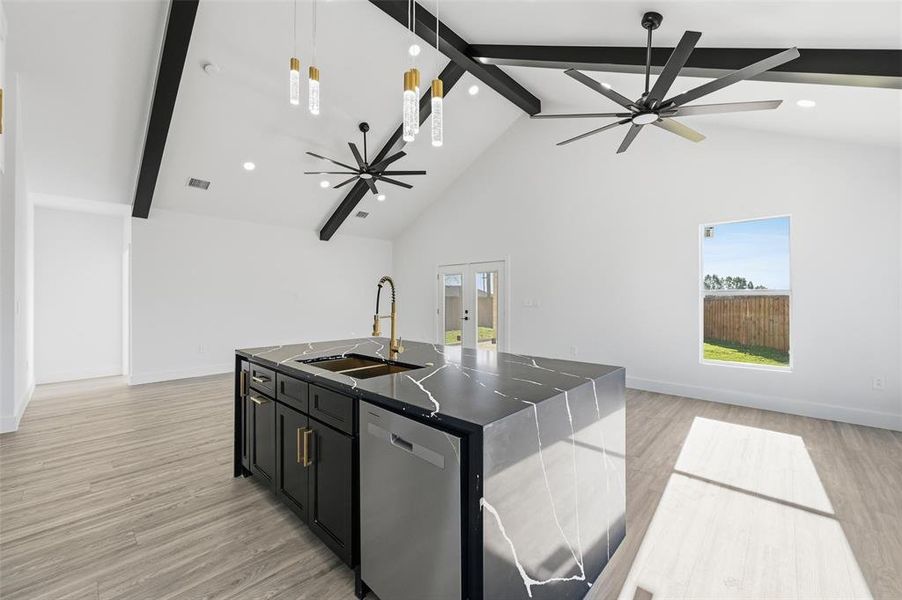 Kitchen featuring dark cabinetry, open floor plan, french doors, a center island with sink, and light wood finished floors Kitchen featuring dark cabinetry, open floor plan, french doors, a center island with sink, and light wood finished floors