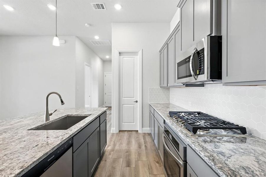 Kitchen featuring light wood-style flooring, stainless steel appliances, light stone counters, recessed lighting, and decorative backsplash Kitchen featuring light wood-style flooring, stainless steel appliances, light stone counters, recessed lighting, and decorative backsplash