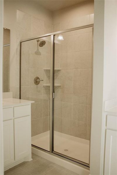 Bathroom featuring tile patterned flooring, vanity, and an enclosed shower