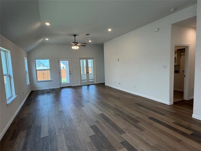 Spacious living area featuring vaulted ceilings, wood-finish flooring, recessed lighting, and a ceiling fan