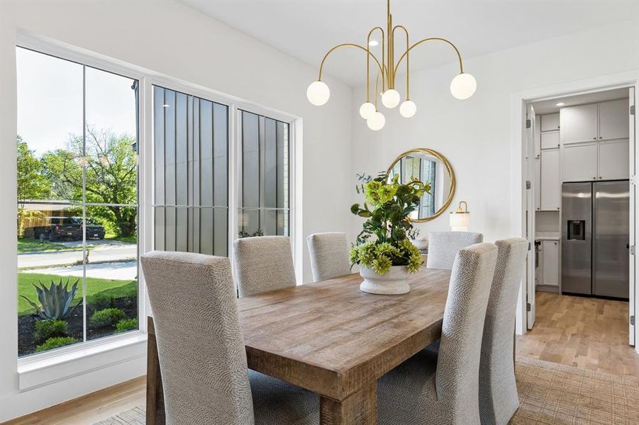 Dining room with light wood finished floors, a chandelier, and healthy amount of natural light