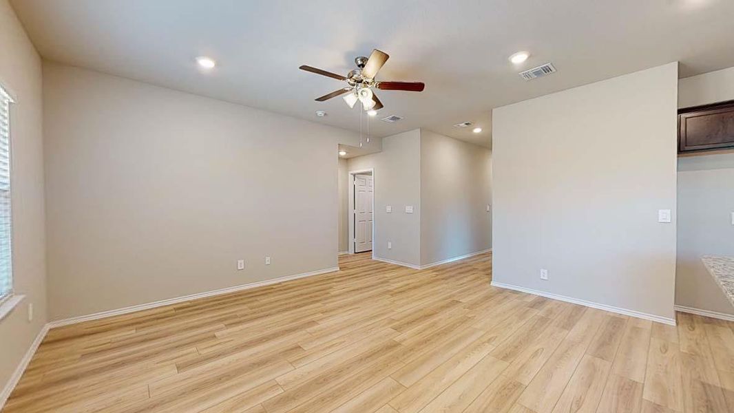 Spacious room featuring wood-finish flooring, neutral-toned walls, and recessed lighting
