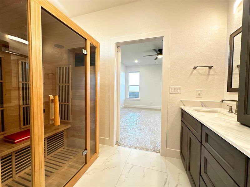 Bathroom with marble finish floor, a ceiling fan, vanity, baseboards, and a sauna