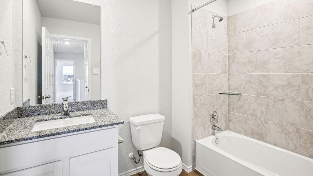Bathroom featuring a white vanity with a granite-finish countertop, undermount sink, and chrome faucet