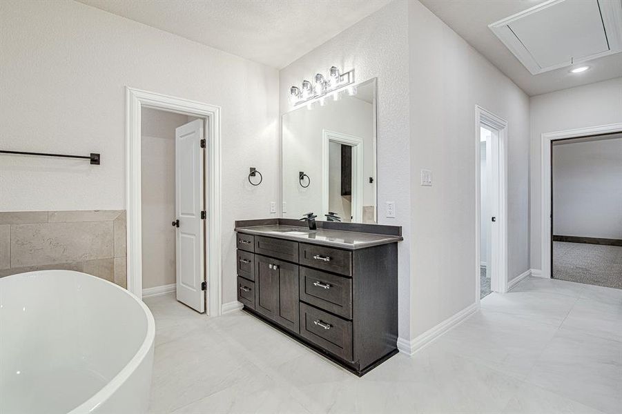 Bathroom featuring a soaking tub, vanity, and baseboards Bathroom featuring a soaking tub, vanity, and baseboards