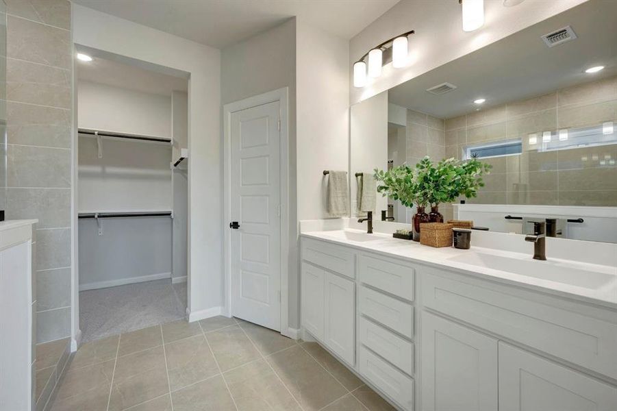 Dual vanity with white cabinetry and integrated sinks, a full-width mirror, and bronze-finish fixtures