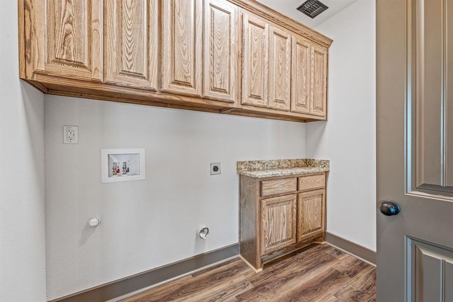 Laundry area featuring dark wood-type flooring, washer hookup, cabinet space, and hookup for an electric dryer