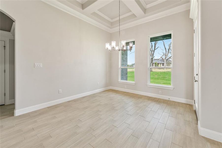 Unfurnished dining area with ornamental molding, wood tiled floors, beamed ceiling, coffered ceiling, and a chandelier