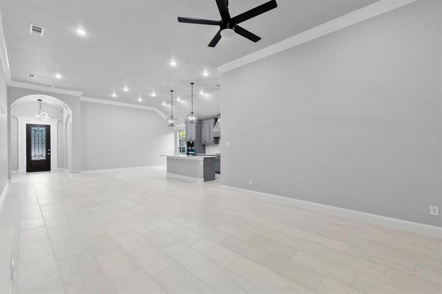 Unfurnished living room featuring ornamental molding and ceiling fan