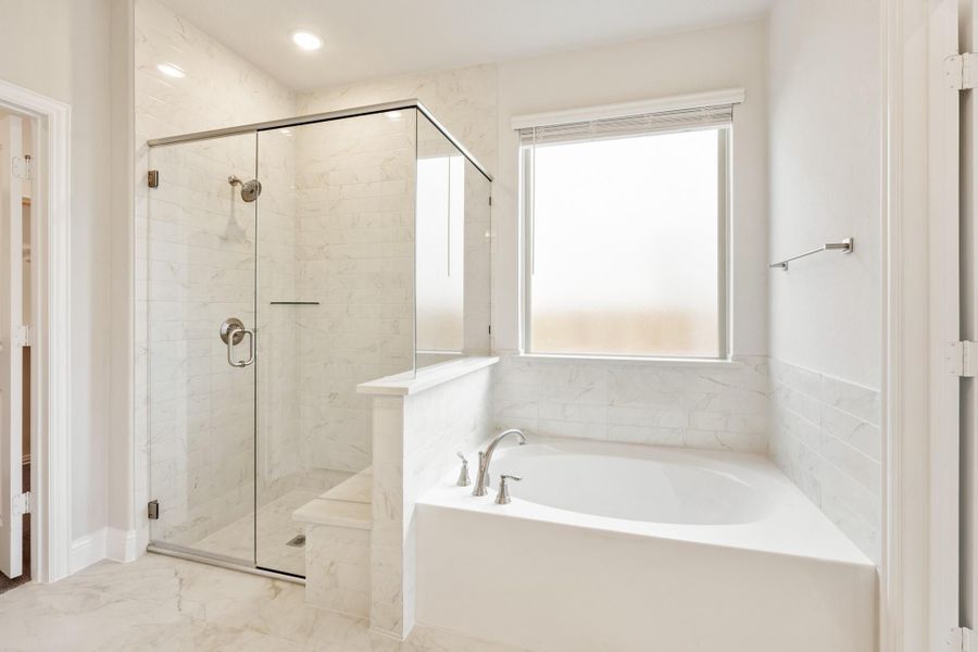 Bathroom with glass-enclosed walk-in shower, soaking tub, and white marble tile walls and floors Bathroom with glass-enclosed walk-in shower, soaking tub, and white marble tile walls and floors
