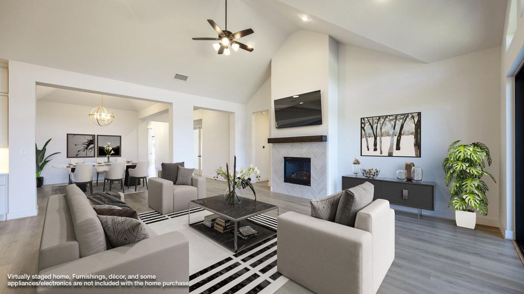 Living room featuring high vaulted ceiling, wood finished floors, a fireplace, a ceiling fan, and a chandelier Living room featuring high vaulted ceiling, wood finished floors, a fireplace, a ceiling fan, and a chandelier