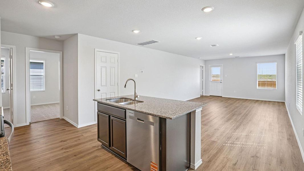 A well-lit open-concept space features durable flooring and a functional kitchen island with integrated sink.