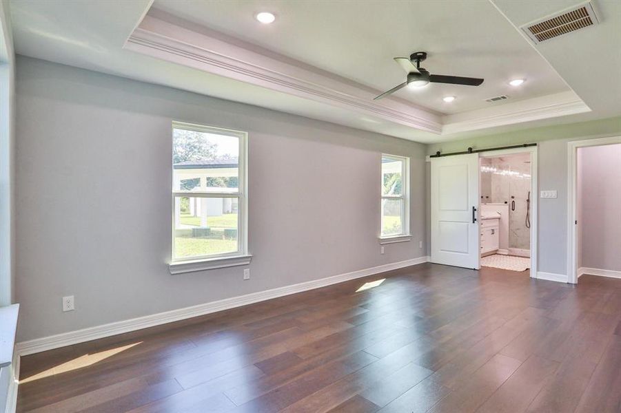 The Size Will Surprise! Spacious primary bedroom with tray ceiling, recessed canned lights and "Bruce Dogwood" engineered wood floors.