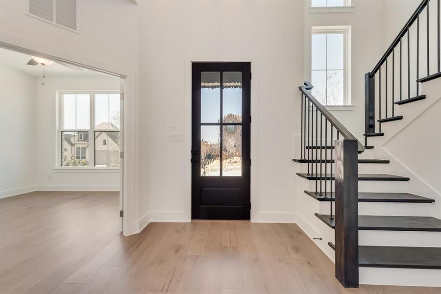 Entryway featuring light wood-style floors, stairway, a high ceiling, and ceiling fan Entryway featuring light wood-style floors, stairway, a high ceiling, and ceiling fan